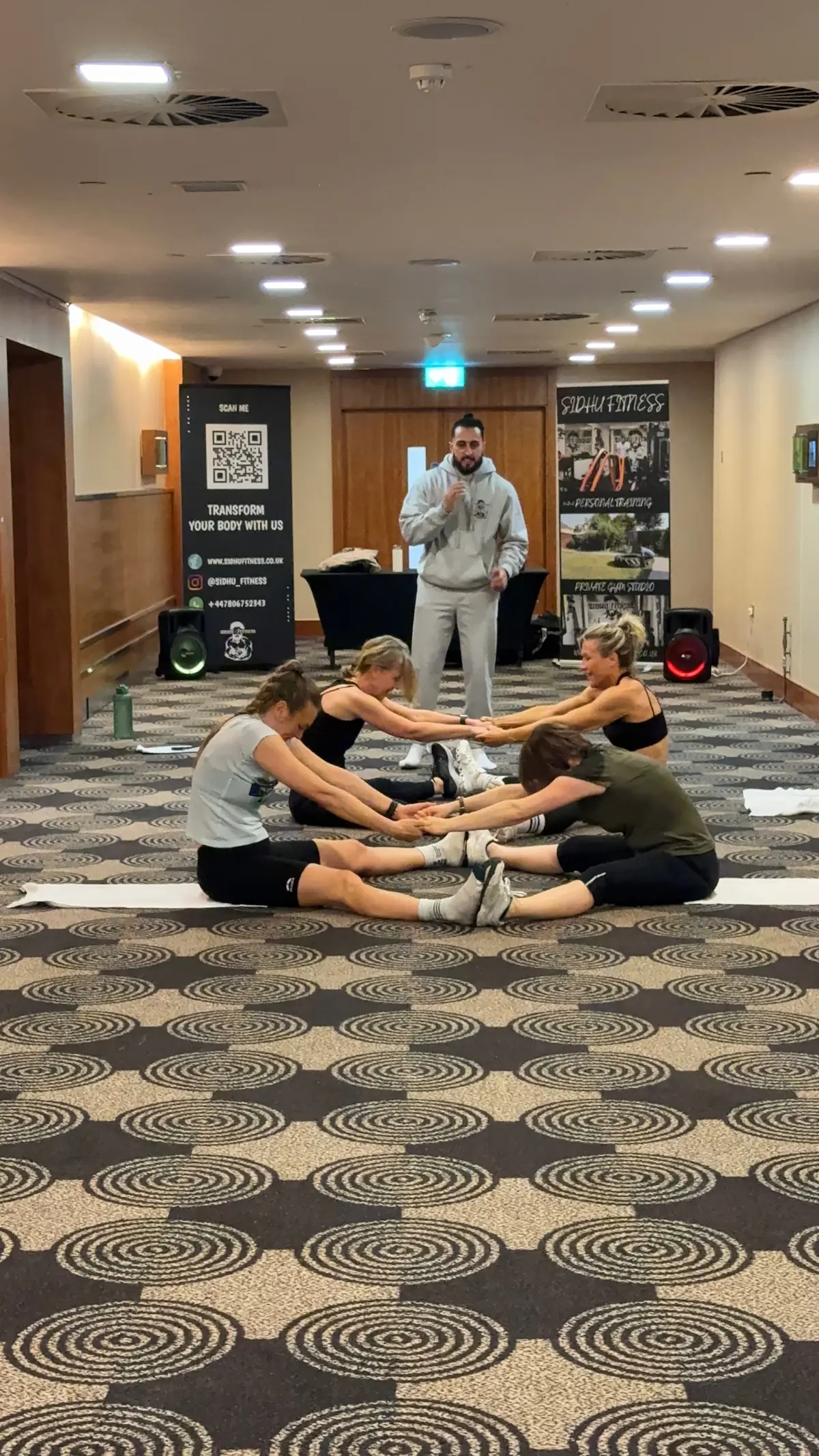Tony Sidhu leading a partner stretching exercise during a Sidhu Fitness corporate wellbeing session