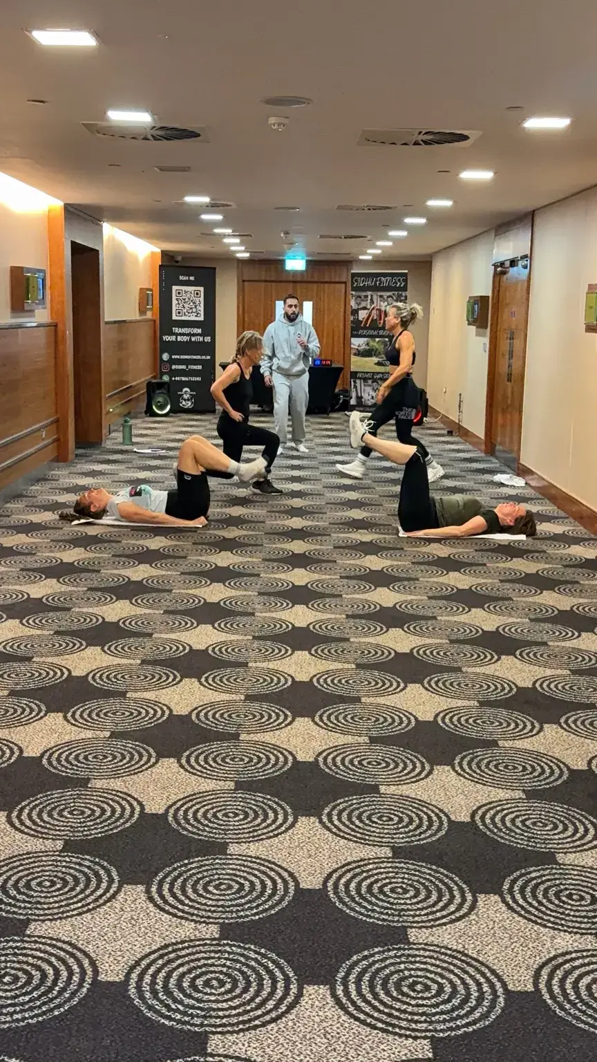 Corporate wellbeing participants completing a floor-based core exercise while Tony Sidhu coaches the group