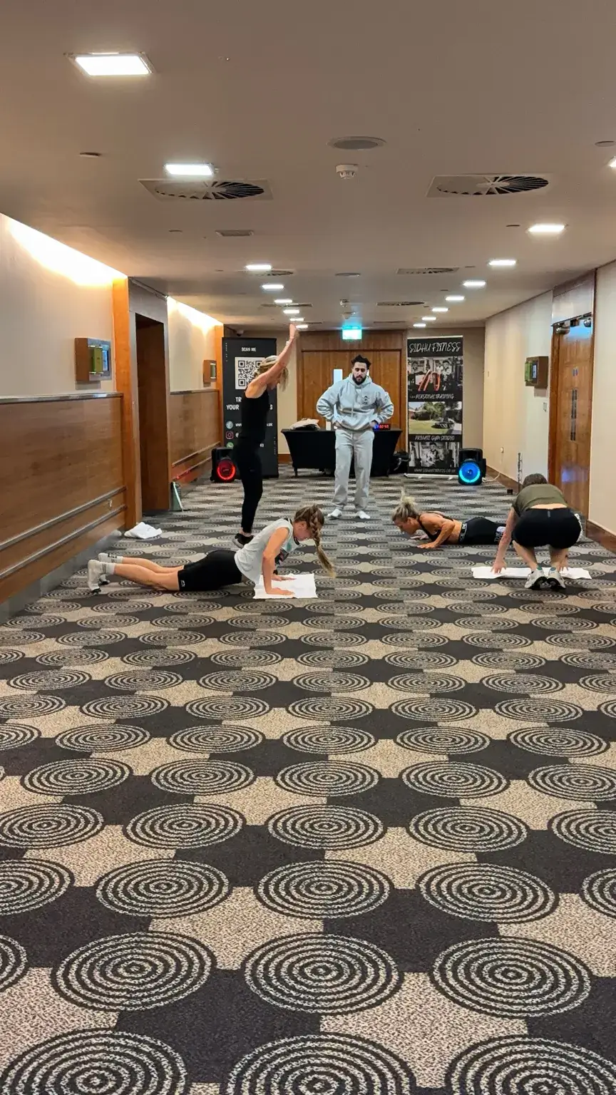 Tony Sidhu coaching a mixed-ability corporate fitness group through a bodyweight circuit