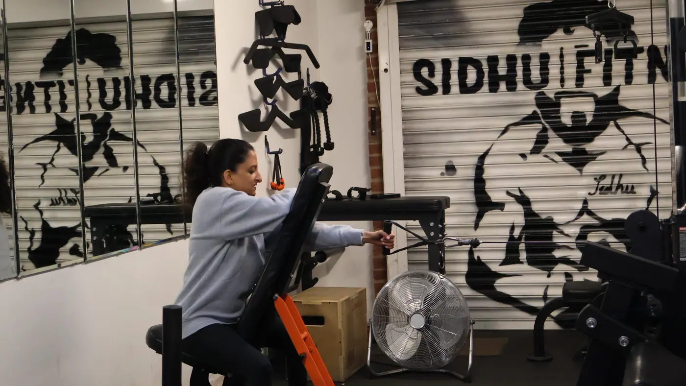 Female Sidhu Fitness client training her back on a cable machine in the private Feltham studio