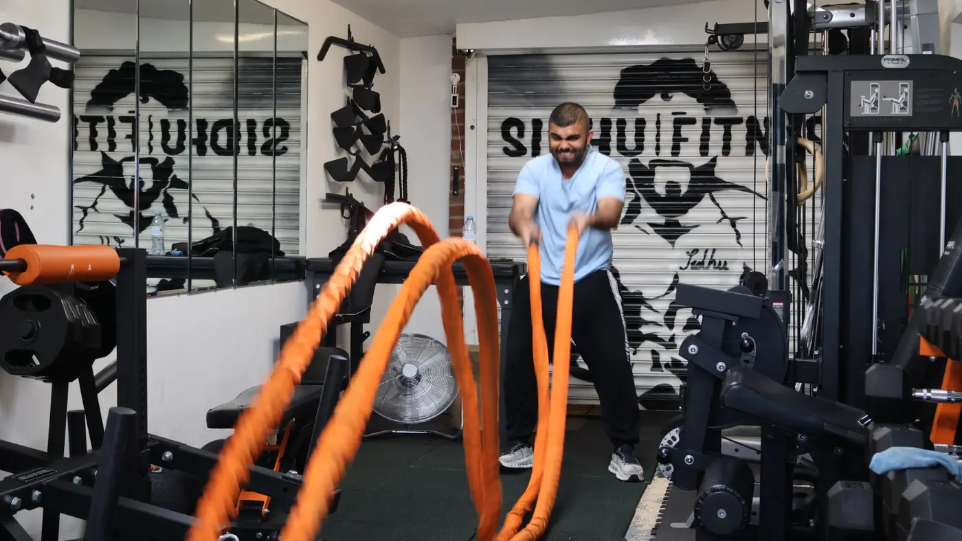 Male personal training client completing battle-rope conditioning at Sidhu Fitness