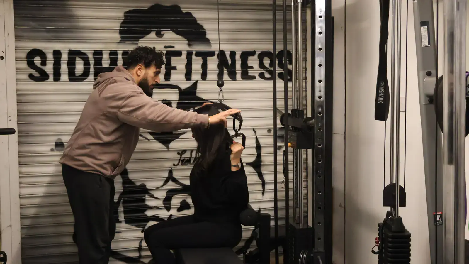 Tony Sidhu coaching a female client through her cable pulldown position in the private studio