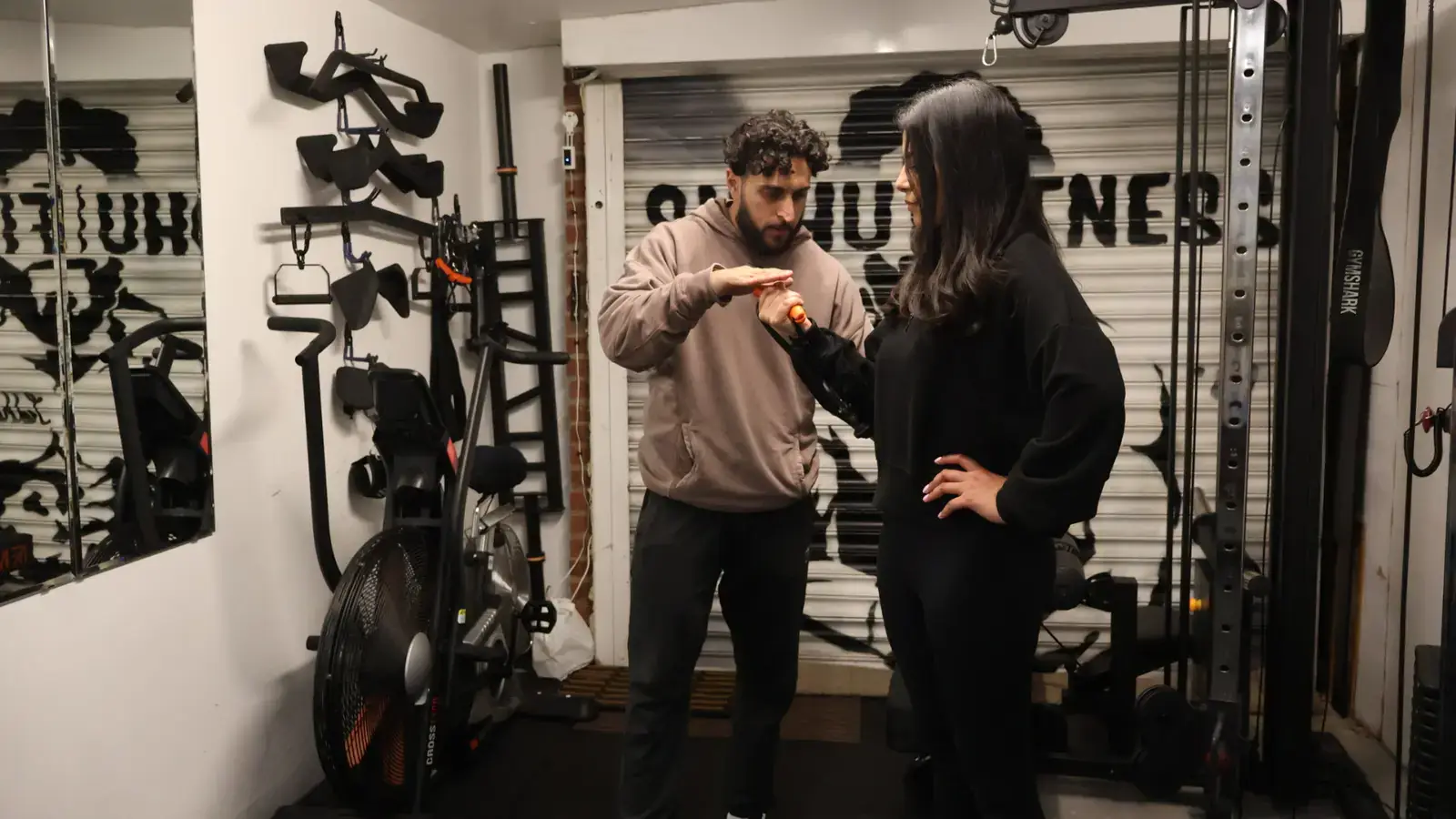 Tony Sidhu demonstrating hand position to a female personal training client in the Sidhu Fitness studio